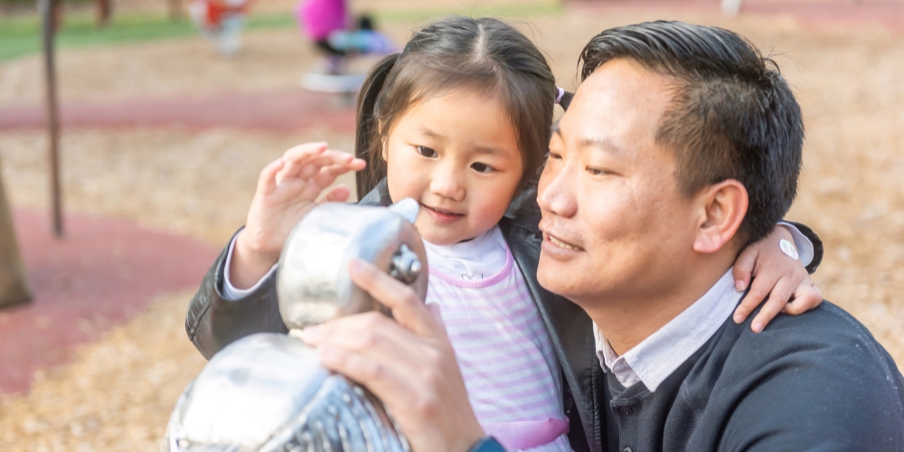 Father and daughter looking at a statue in a playground