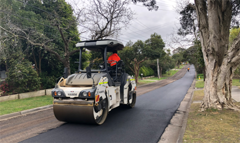 Road resurfacing machine rolling along new road surface